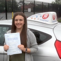 Emiily Davis – Jim #3 200 Smiling Emily Davis holding her practical driving test certificate next to the JSF Driving School car.