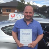 Dan O’Regan – Jim #3 200 Dan O'Regan smiling whilst holding his practical driving test pass certificate beside the JSF Driving School car