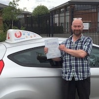 Andy Ashford-Kelleher raving review New driver Andy Ashford-Kelleher proudly holding his practical driving test pass certificate beside the JSF Driving School car