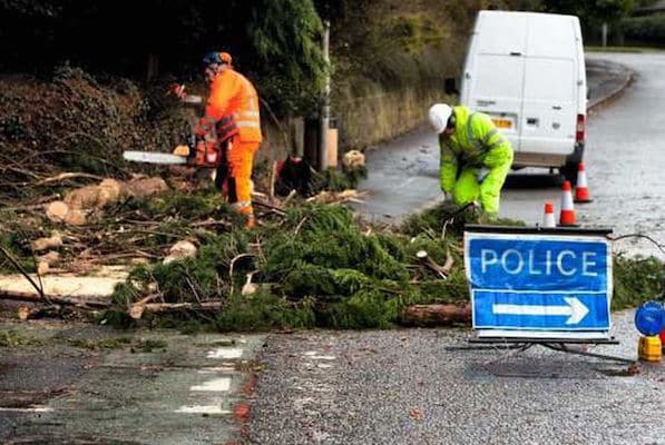 Police sign diverting traffic after high winds cause a fallen tree to be removed by workmen