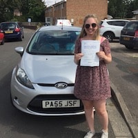 Charlotte Willcocks proudly holding her new practical test certificate standing next to the school car 