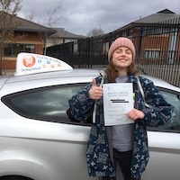 New driver Annie Humphrey with her first time practical driving test pass certificate next to the JSF Driving School car