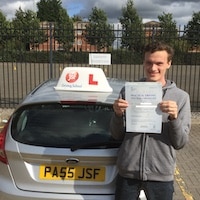 New driver Tom Rogerson smiling outside holding his pass certificate beside the JSF Driving School car